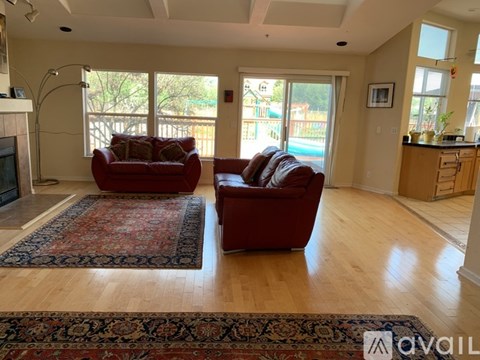 Two red couches in a living room with a fireplace and sliding glass doors.