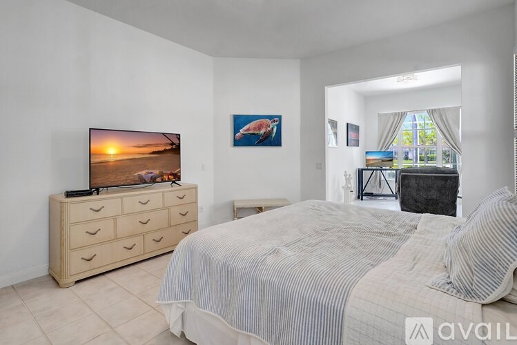 A bedroom with a large bed, a television, and a painting on the wall.