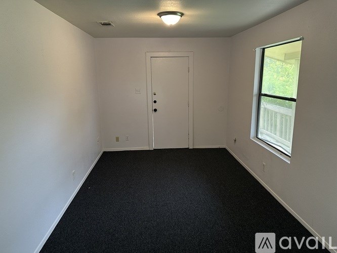 A room with a door, a window, and a carpeted floor.