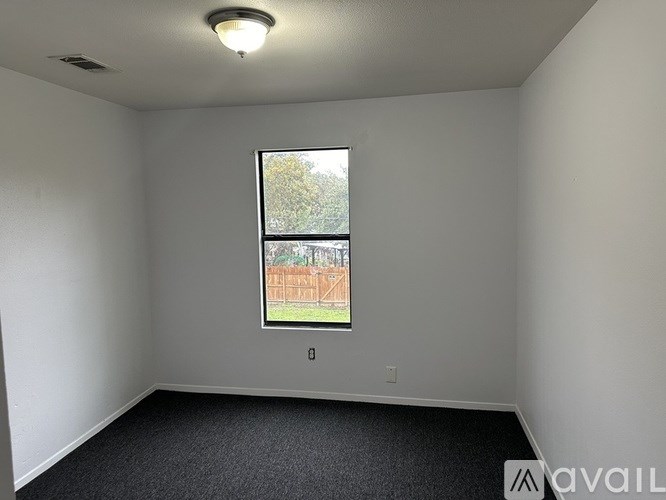 A room with a window showing a fence and trees outside.