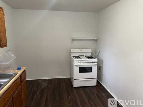 A white stove is in a kitchen with wood floors and white walls.