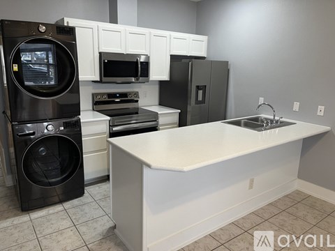 A kitchen with a black dishwasher and white cabinets.