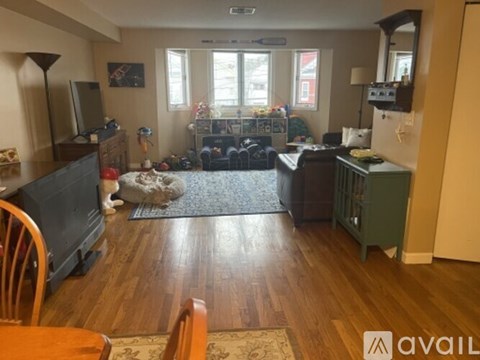 A cat is sitting on a rug in the middle of a living room.