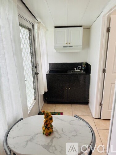 A white table with a yellow vase on it in a kitchen.