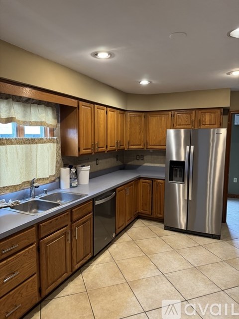 A kitchen with wooden cabinets and a stainless steel refrigerator.