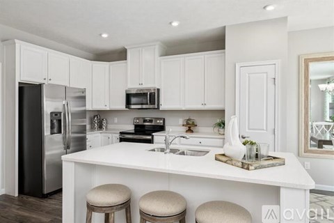 A kitchen with white cabinets and a stainless steel refrigerator.