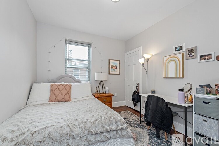 A bedroom with a bed, desk, chair, and a window.