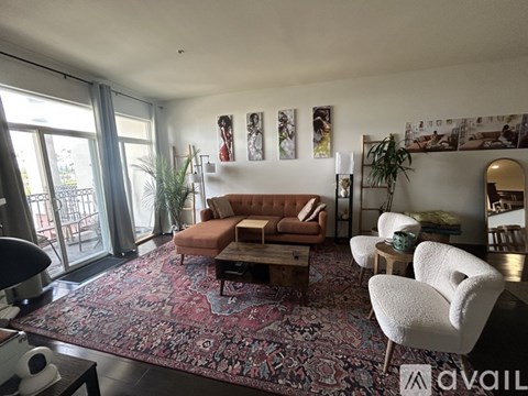 A living room with a red rug and a brown sofa.