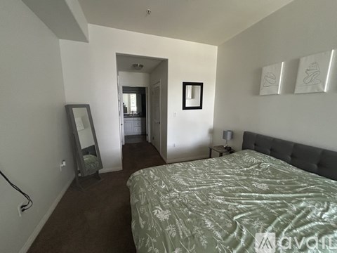 A bedroom with a bed, dresser, mirror and wall art.