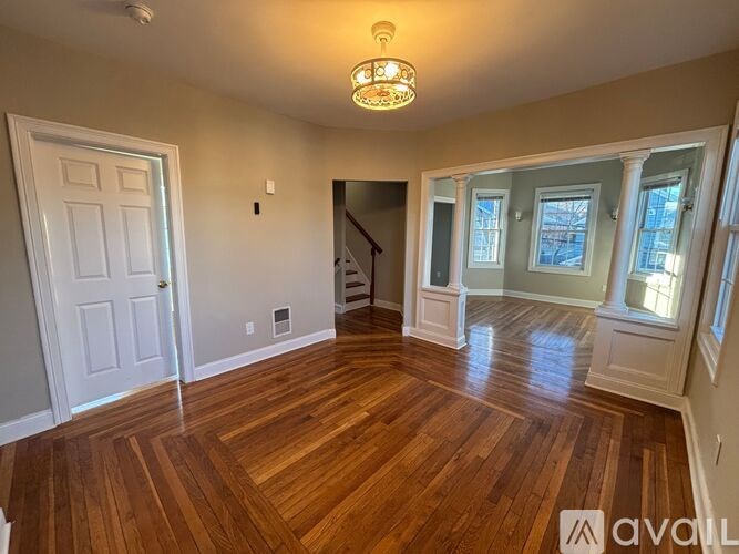 A living room with hardwood floors and a staircase in the background.