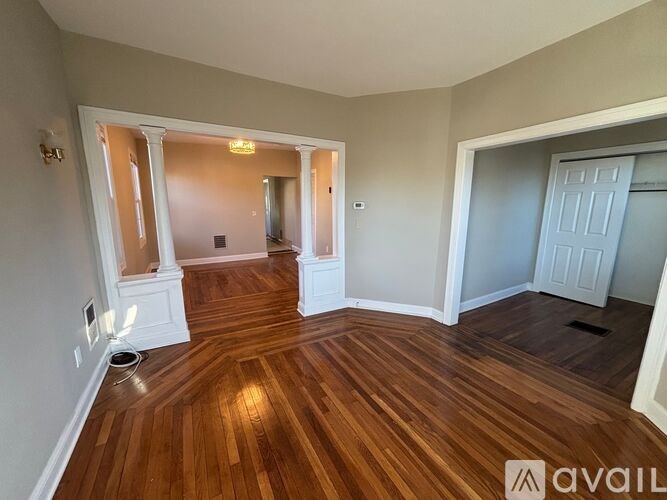 A room with wooden floors and white walls is available for rent.