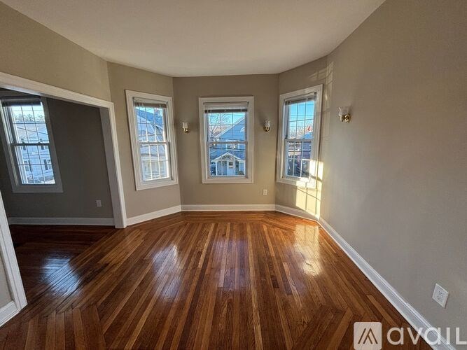 A room with wooden floors and three windows.
