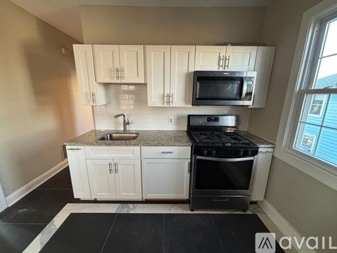A kitchen with white cabinets and a black stove top oven.