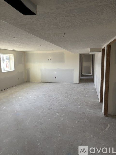 A room with a concrete floor and walls, a window, and a door is available for rent.