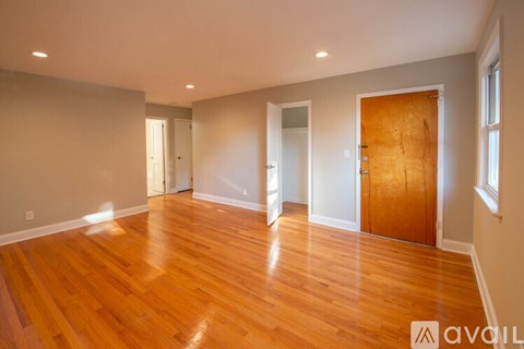 A room with wooden floors and white walls, with a door on the right side.