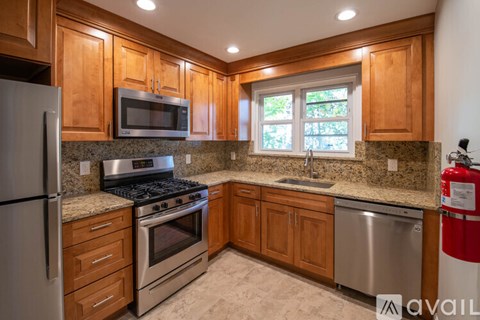 A kitchen with wooden cabinets and a stainless steel dishwasher.