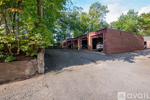 A red brick building with a garage door open is surrounded by trees.