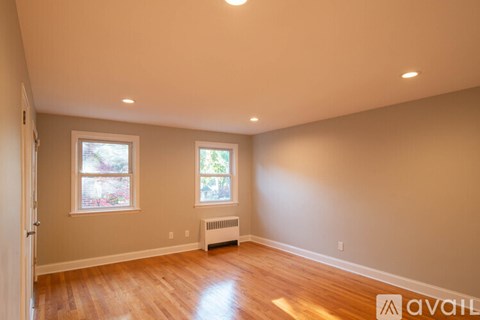 A room with wooden floors and two windows.