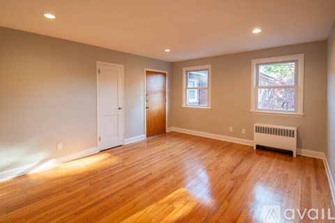 A room with wooden floors and a window with a view of trees.