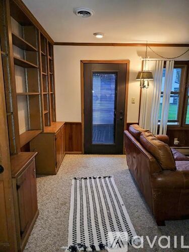 A living room with a brown leather couch and a black and white rug.