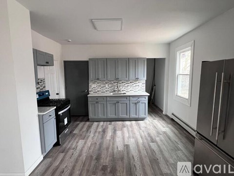 A kitchen with a black countertop and grey cabinets.