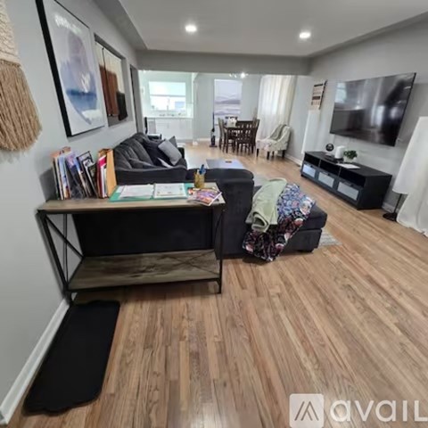 A living room with a black couch and a wooden floor.