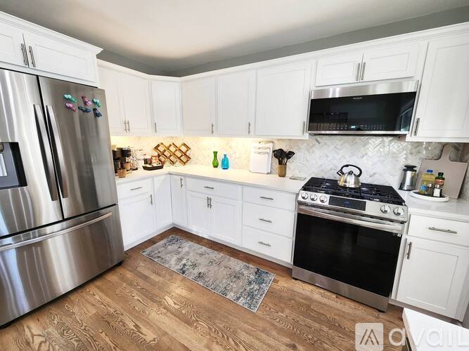 A kitchen with white cabinets and a stainless steel refrigerator.