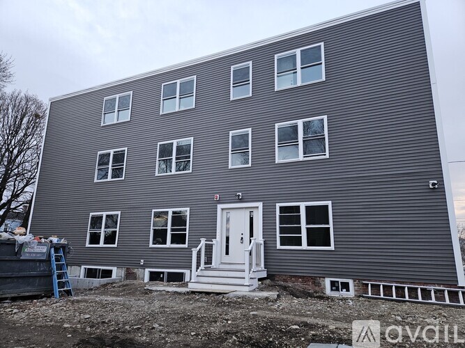 A grey building with a white door and windows.