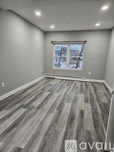 A room with wooden flooring and a window showing a view of buildings outside.