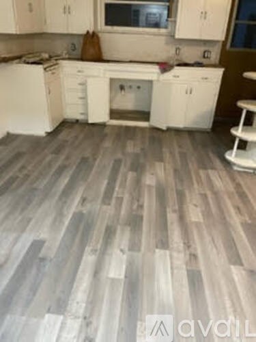 A kitchen with white cabinets and a wooden floor.