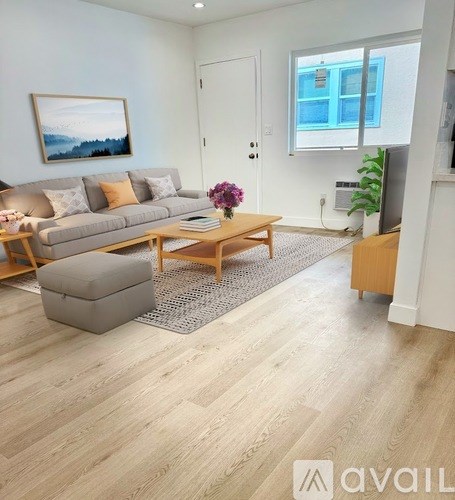 A living room with a grey couch, a wooden coffee table, and a painting on the wall.