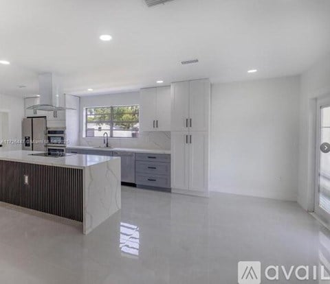 A modern kitchen with white cabinets and a marble island.