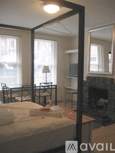 A bedroom with a bed, chair, and a fireplace.