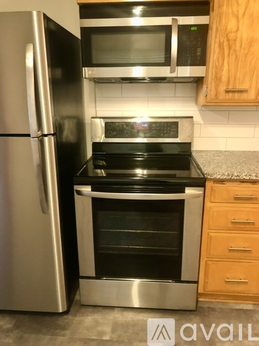 A kitchen with a stainless steel refrigerator, microwave, and oven.