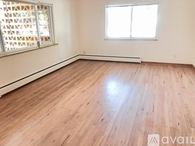 A room with wooden flooring and a window with blinds.