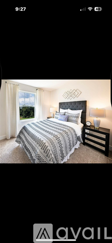 A bedroom with a bed, nightstand, and window.