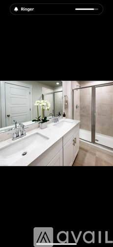 A white bathroom with a sink, mirror, and a vase of flowers.