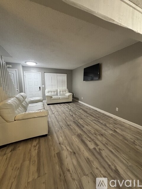 A living room with a white couch and a television on the wall.