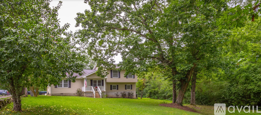 A house is surrounded by trees and has a lawn in front.