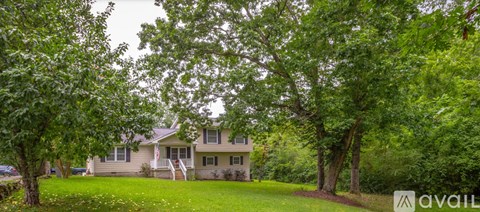 A house is surrounded by trees and has a lawn in front.