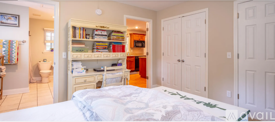 A bedroom with a white bed and a built in bookshelf.