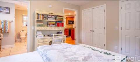 A bedroom with a white bed and a built in bookshelf.