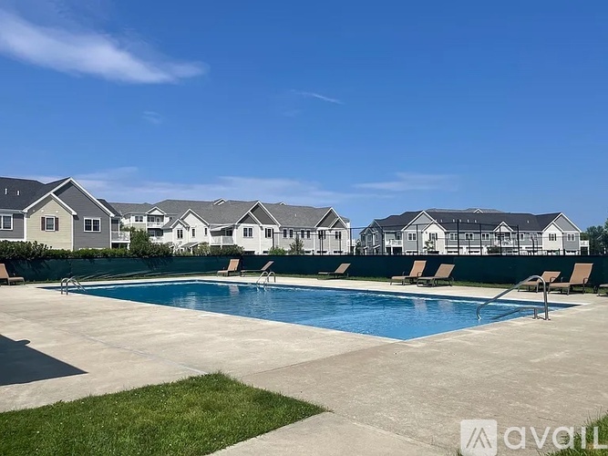 A swimming pool surrounded by lounge chairs and houses in the background.