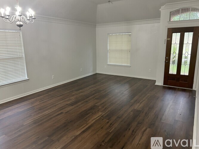 A room with wooden flooring and a chandelier.