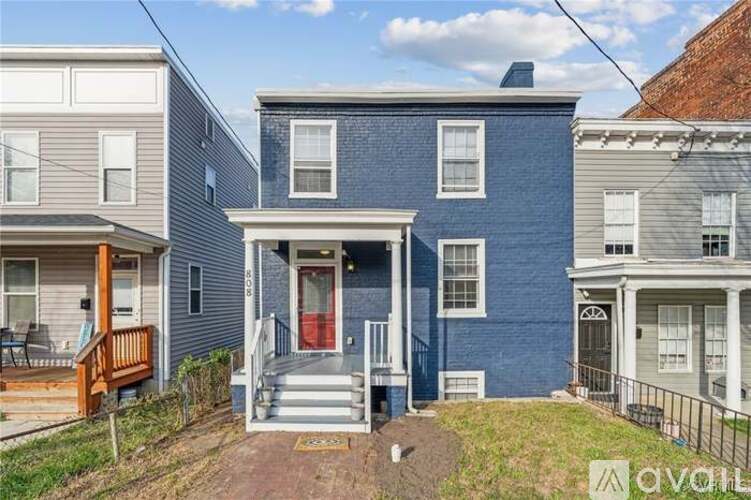 A blue house with a red door is in front of two other houses.