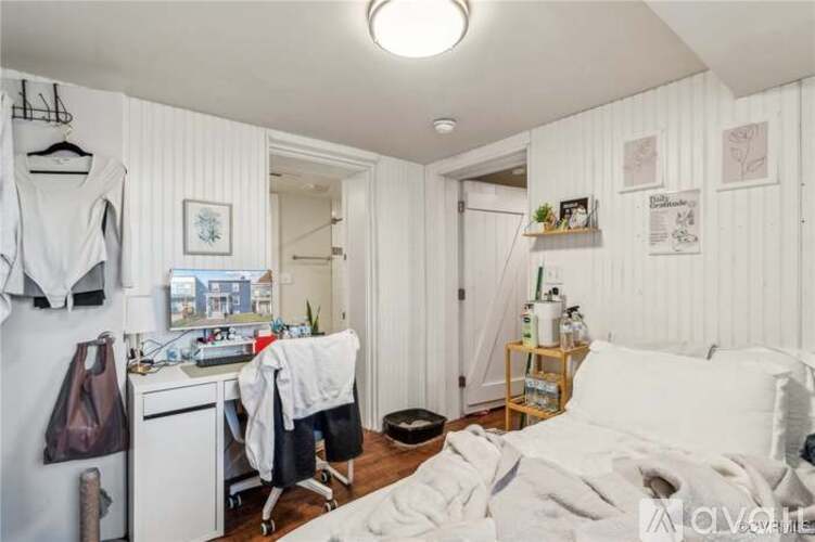 A bedroom with a bed, a chair, and a small table with a lamp on it.