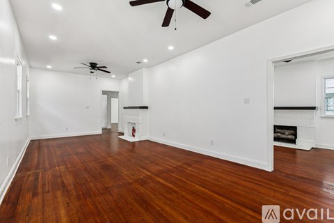 A spacious room with wooden floors and a ceiling fan.