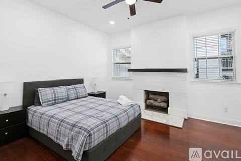 A bedroom with a bed, dresser, and fireplace.
