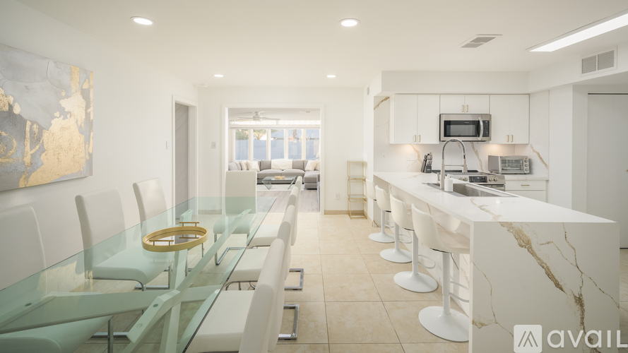 A modern kitchen with a glass table and white chairs.
