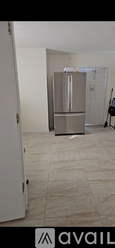 A kitchen with a fridge and a door open.